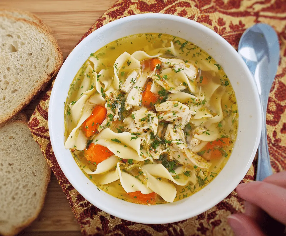 A warm bowl of homemade Grandma’s Chicken Noodle Soup featuring tender chicken, vegetables, and egg noodles in a comforting broth, served with fresh herbs.