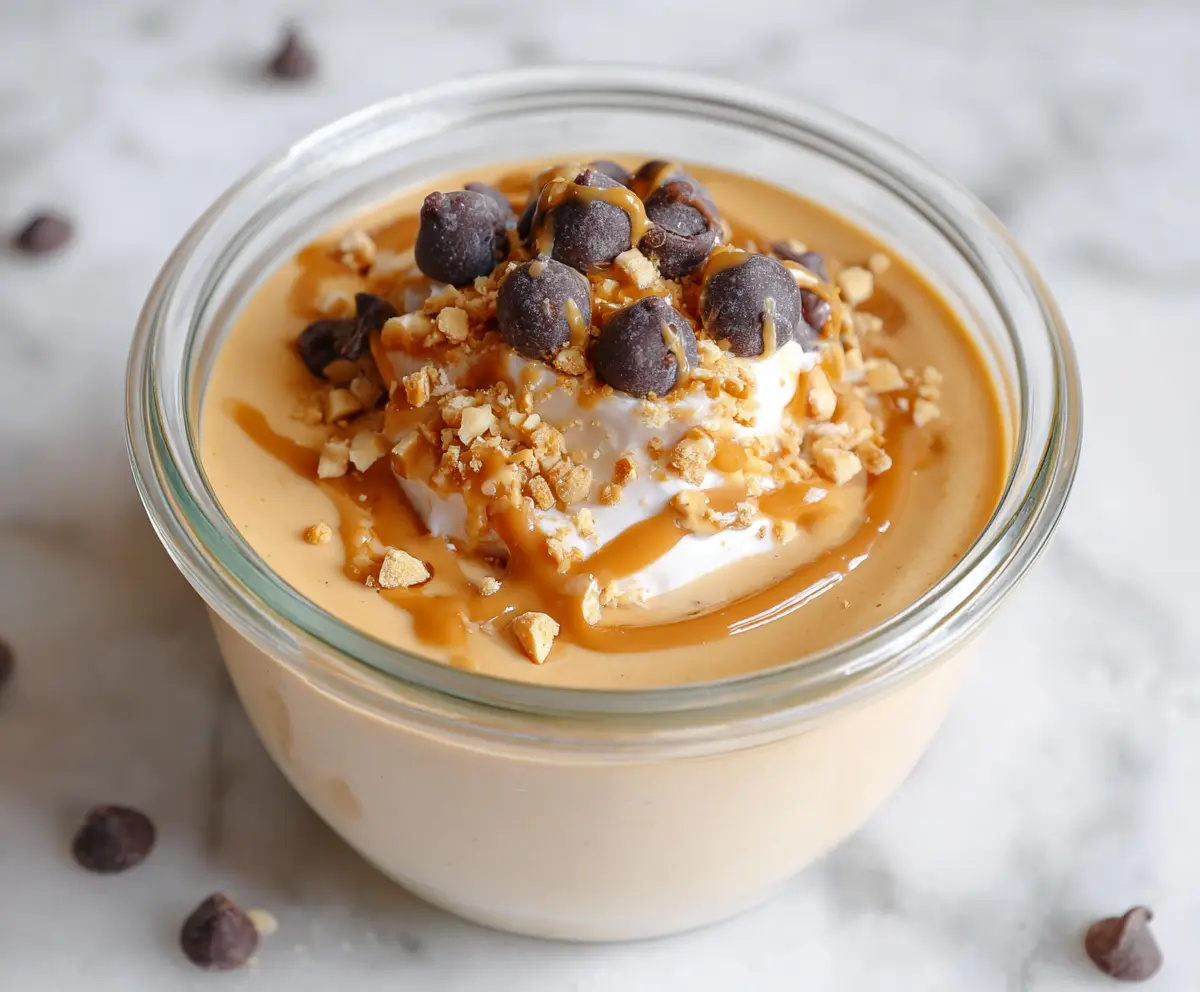 Creamy Greek Yogurt Peanut Butter Protein Pudding in a glass bowl with a spoon on a wooden table.