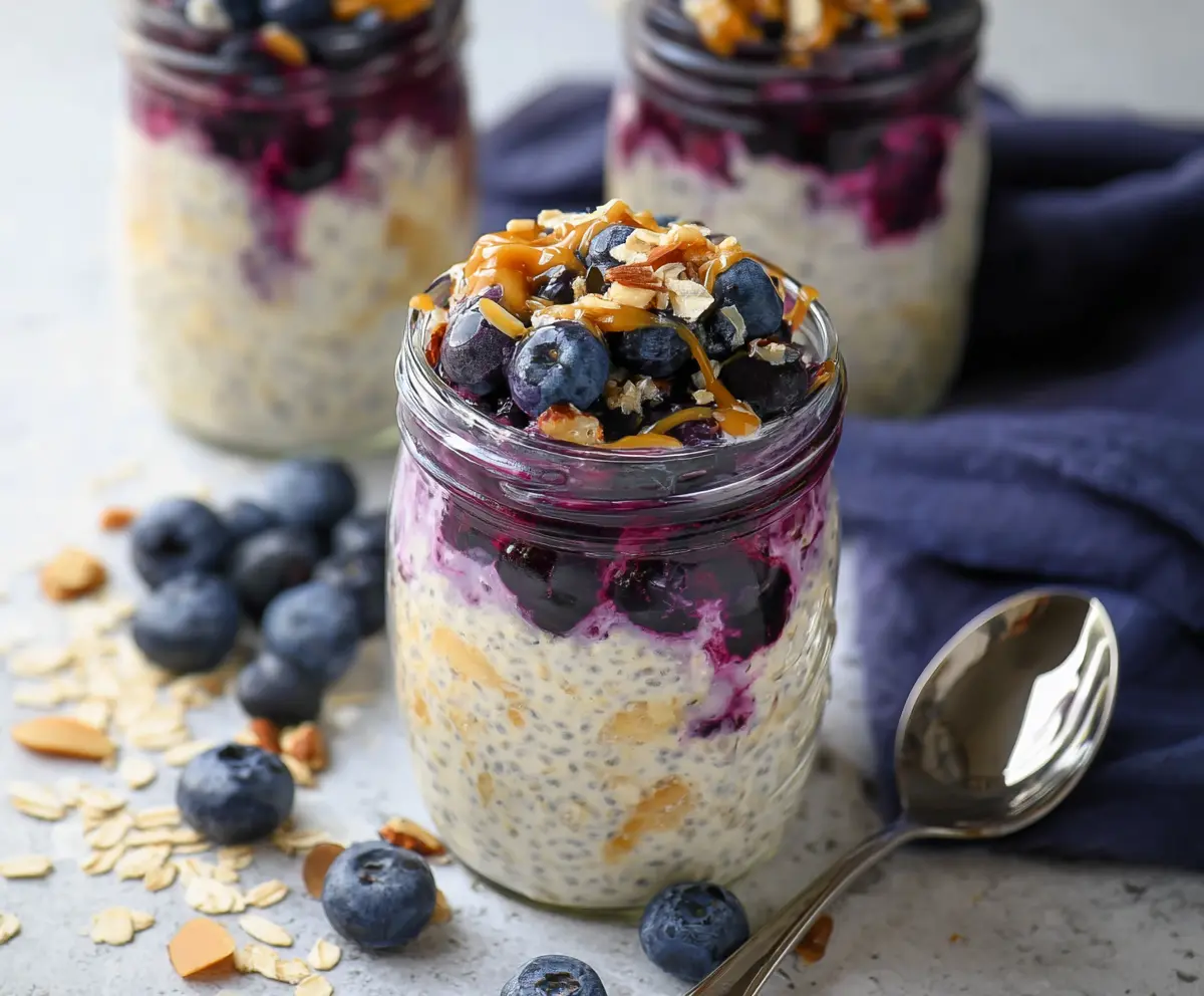 Creamy blueberry cheesecake overnight oats topped with fresh blueberries and a graham cracker crust.