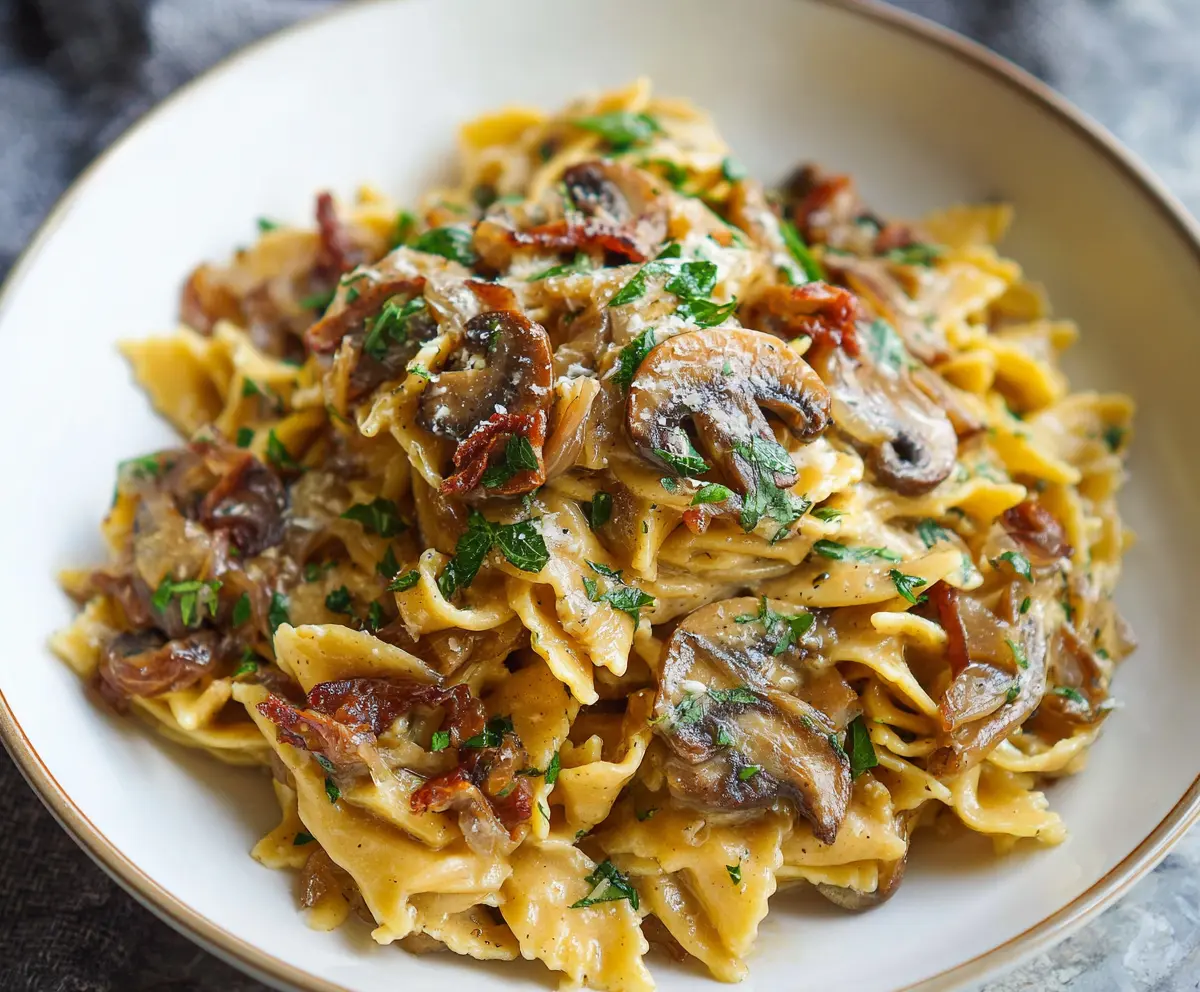 Delicious caramelized onion pasta garnished with herbs on a rustic plate.