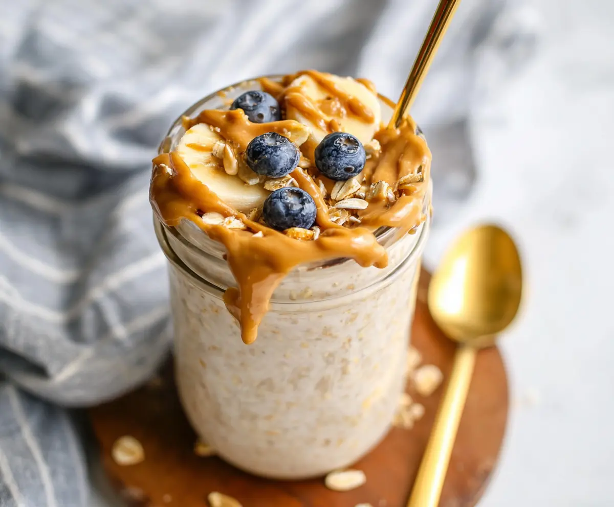 Creamy peanut butter overnight oats in a glass jar topped with sliced bananas and chia seeds.