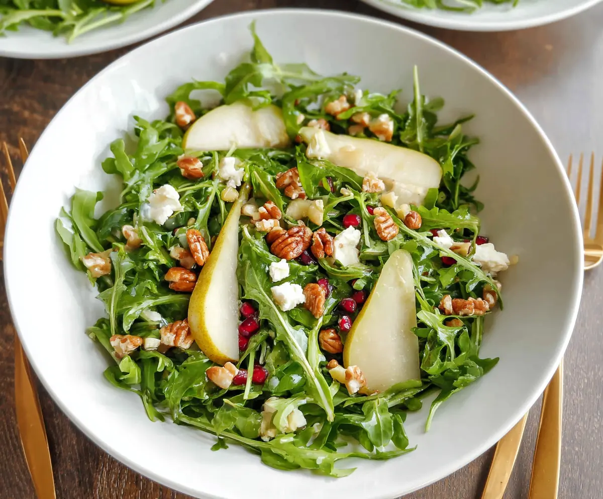 Fresh arugula and juicy pear salad garnished with nuts and cheese, perfect for a light, healthy meal.