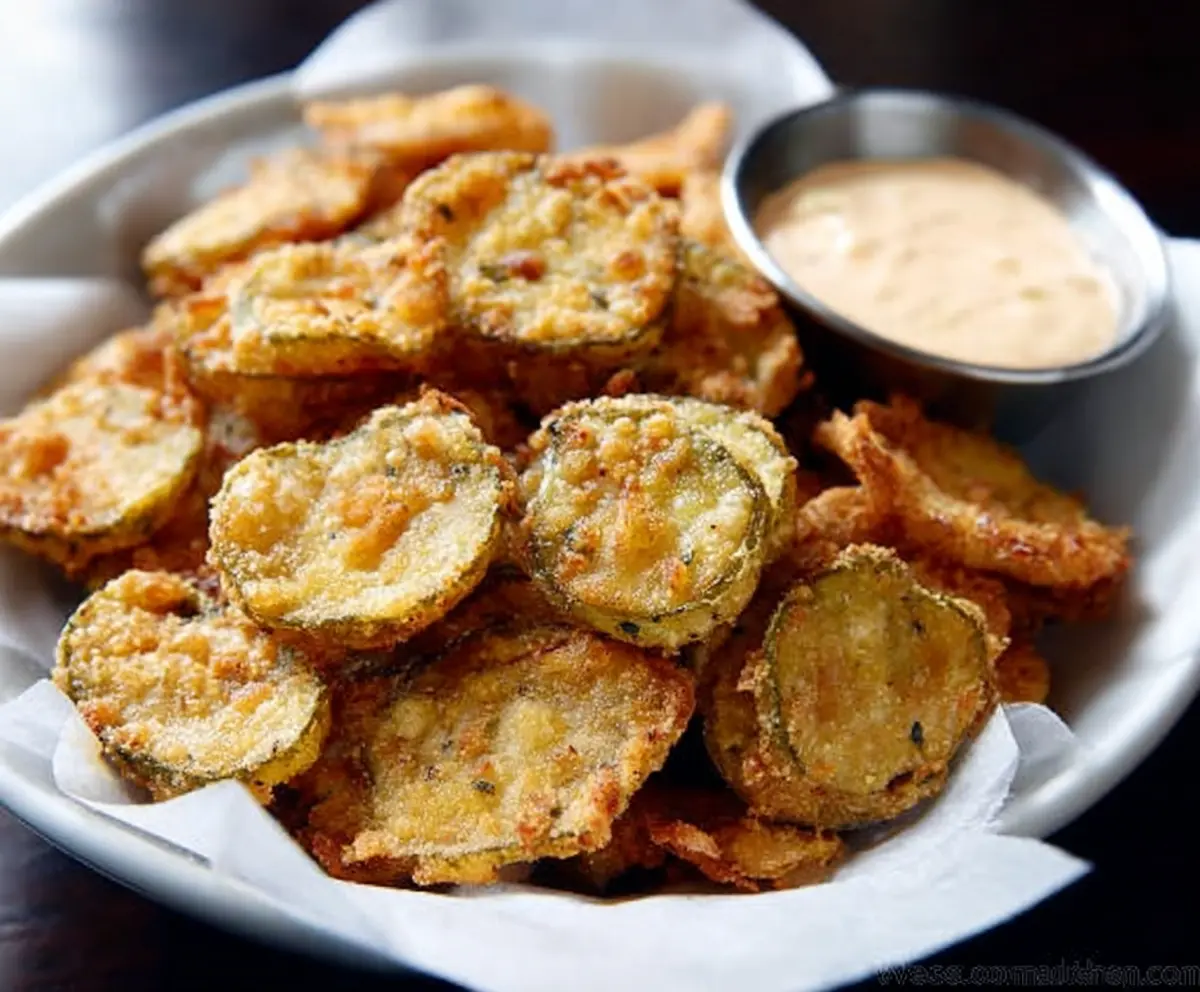 Crispy fried pickles served with tangy dipping sauce on a rustic plate