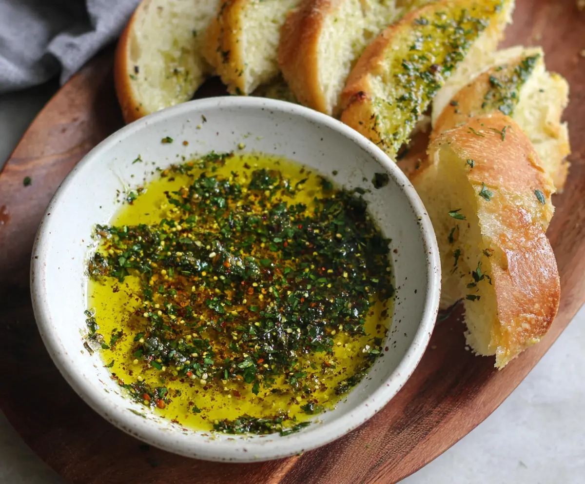 Delicious olive oil bread dip with herbs served in a rustic bowl.