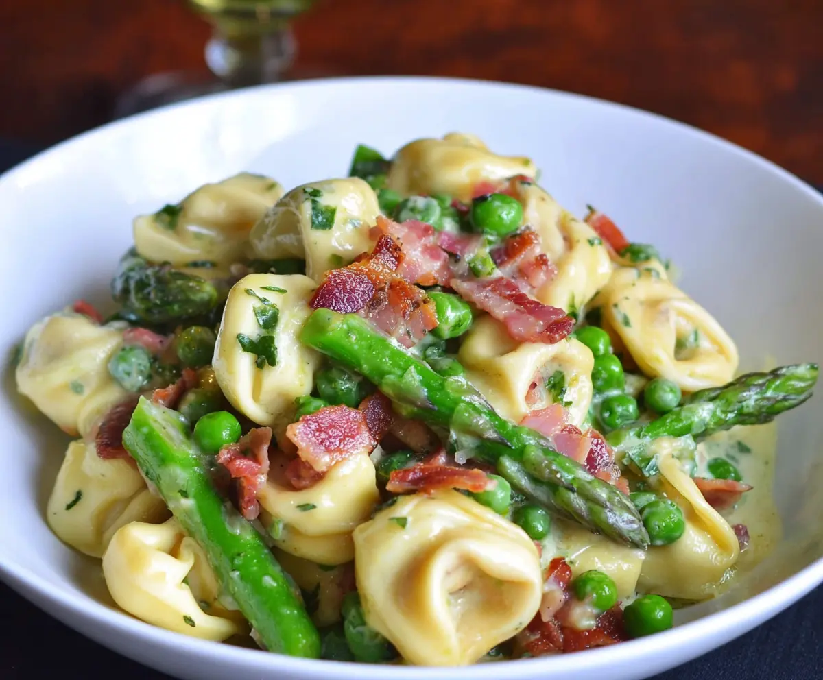 Delicious tortellini pasta with peas, asparagus, and crispy bacon on a plate.